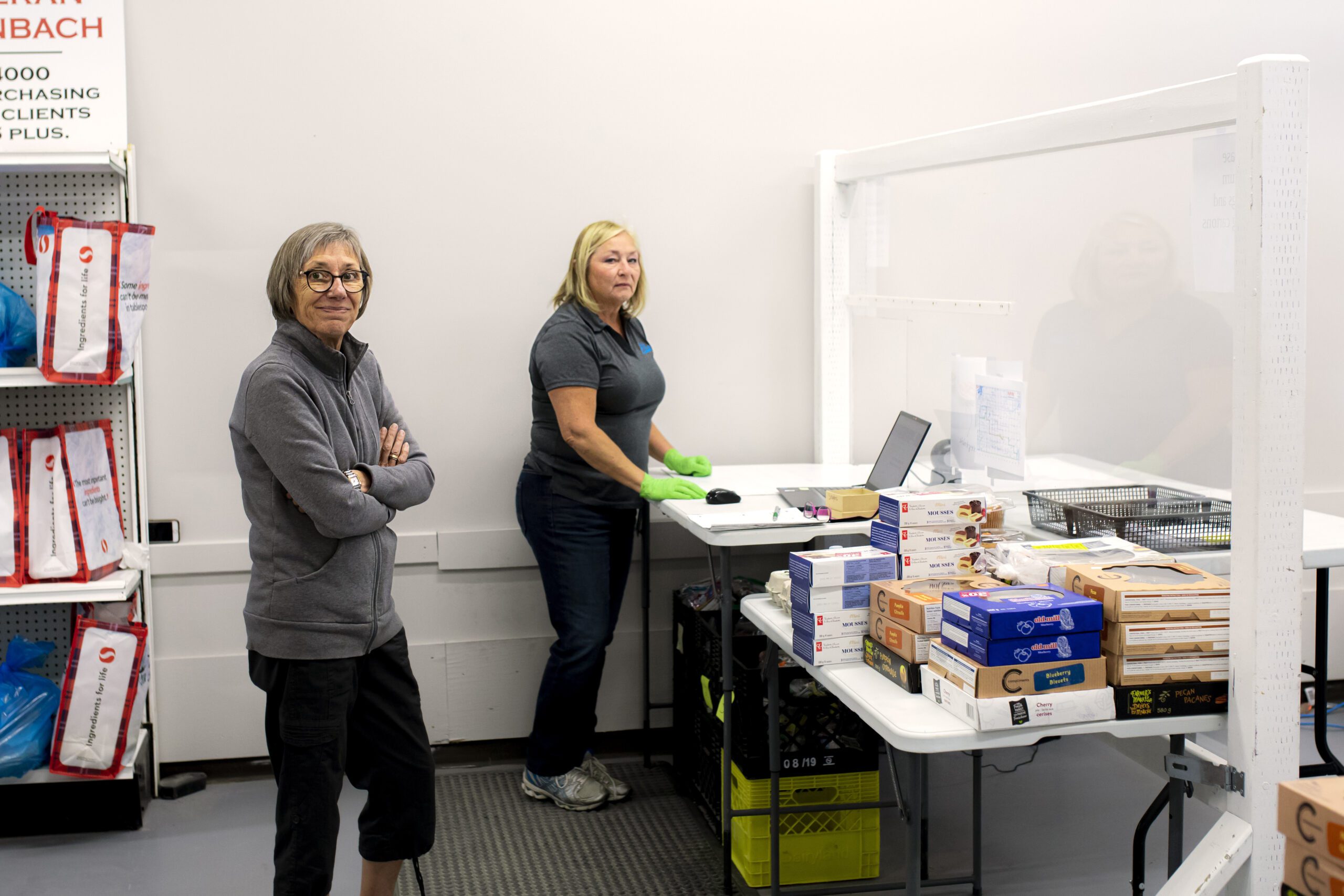 man holding a box of food with people sorting food behind him